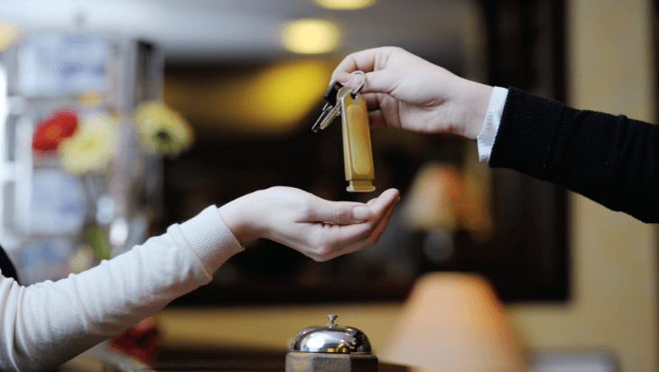 Front desk staff handing hotel room keys to a guest, representing hotel service and customer satisfaction.