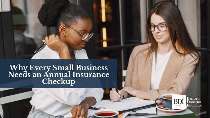 Two businesswomen reviewing paperwork and discussing documents at a caf&eacute; table with coffee mugs.